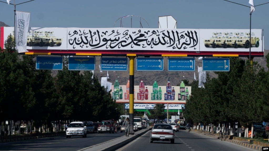 FILE - Commuters drive under a banner placed by Taliban authorities, near the Kabul airport, Aug. 30, 2022. Taliban allegedly barred 100 female students from leaving Afghanistan for the United Arab Emirates in August 2023, where they were to enroll in university studies. 