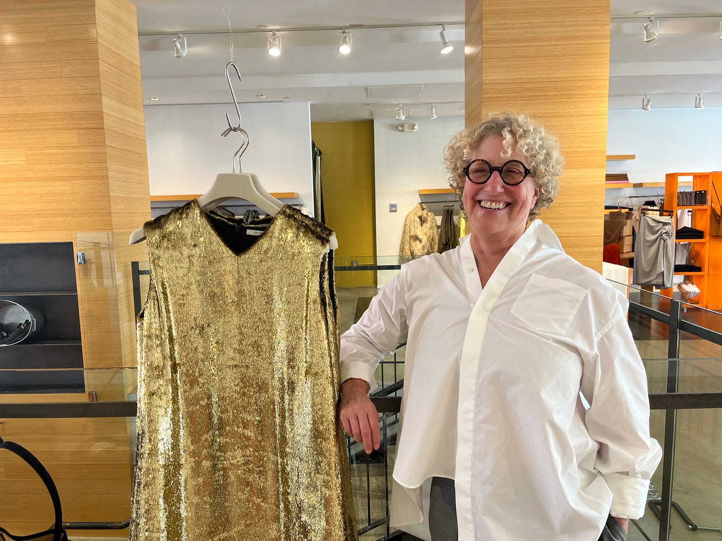 Nancy Pearlstein poses with a shimmery gold dress in her store, Relish.