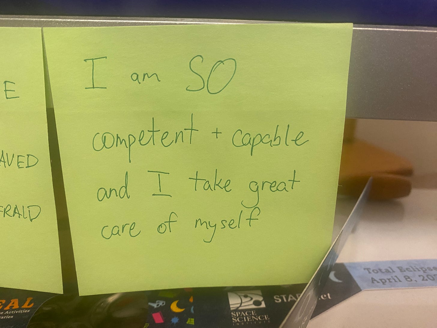 Green Post-It with the words "I am SO competent + capable and I take great care of myself"