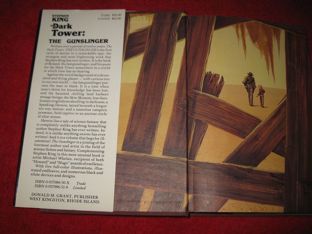 A first edition of THE GUNSLINGER is open to show the endpapers with the front dustjacket flap partially covering the left board.