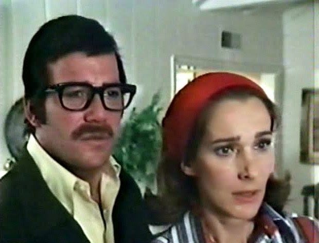 William Shatner, in the thickest framed glasses ever lenscrafted, stares in shock with Julie Adams at something just off screen.