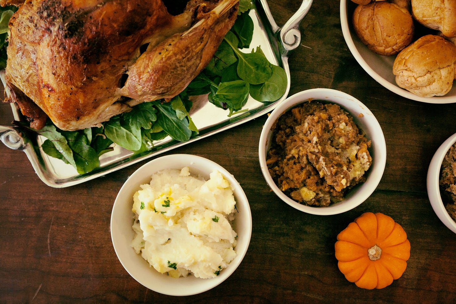 Thanksgiving spread with turkey, mashed potatoes, stuffing, and bread rolls