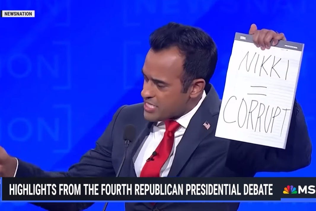 Video screenshot of Vivek Ramaswamy holding up a pad of paper on which is written in Sharpie, 'NIKKI = CORRUPT'