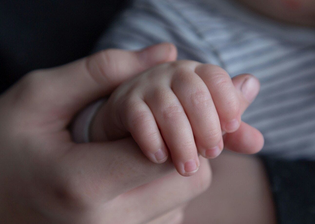 A mom holding a babies hands A mom holding a babies hands