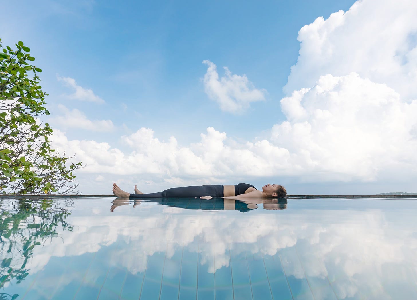 Woman laying in calm pool of water doing breath work