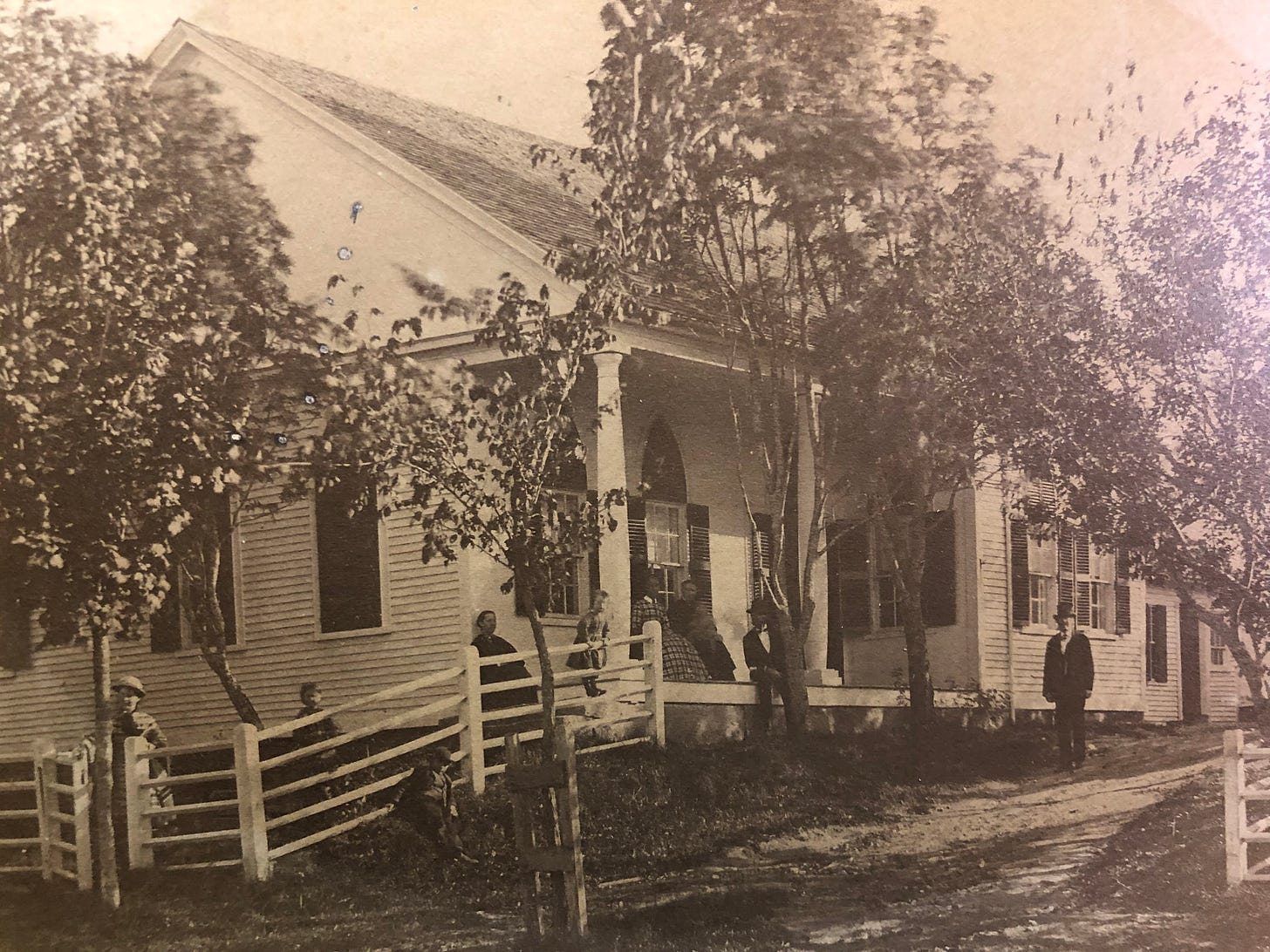 early photo of nine people in front of a house