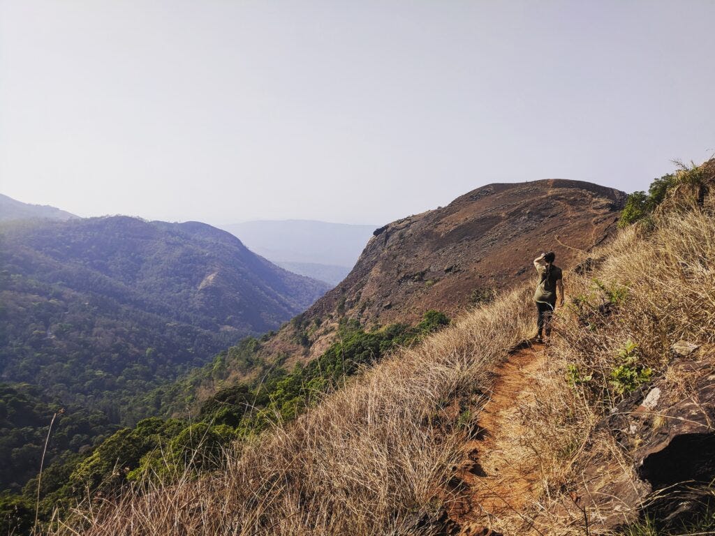 Dee walking down a trail of a hill station in Karnataka, India.