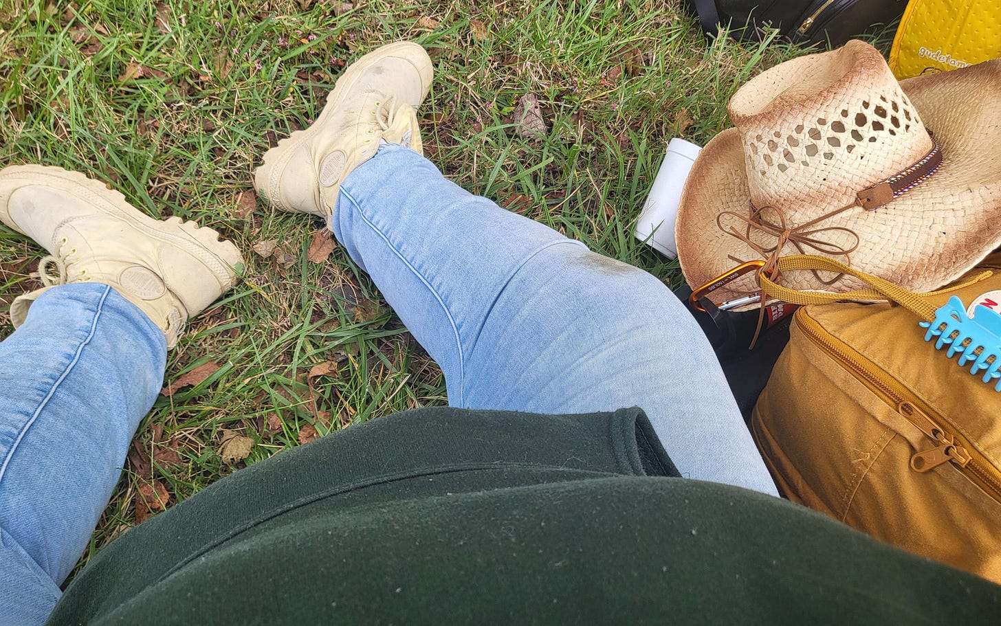 my legs and torso on the grass next to my backpack with my hat attached to it