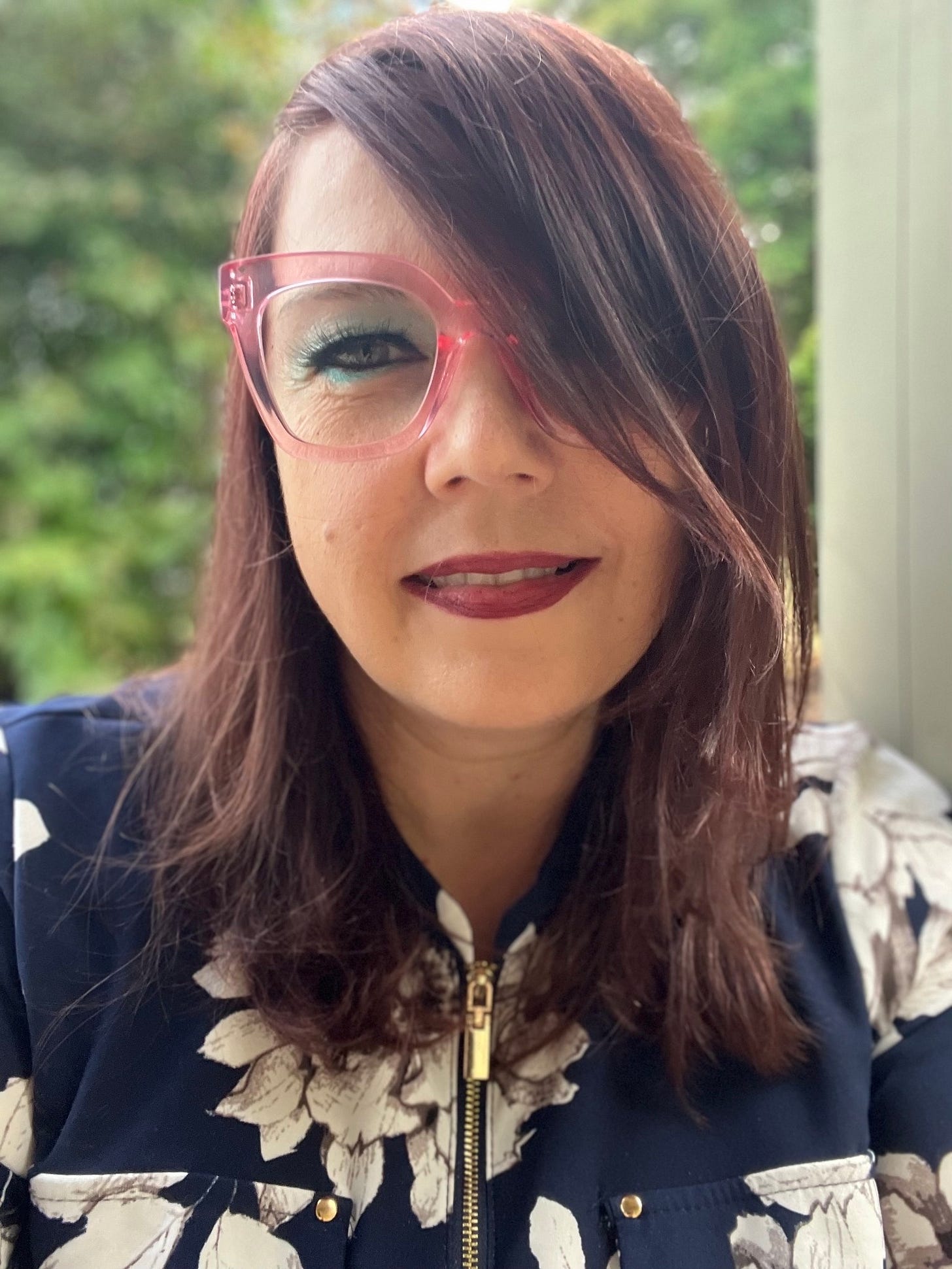 Kathryn Mockler wearing pink eyeglasses and a blue and white floral dress.