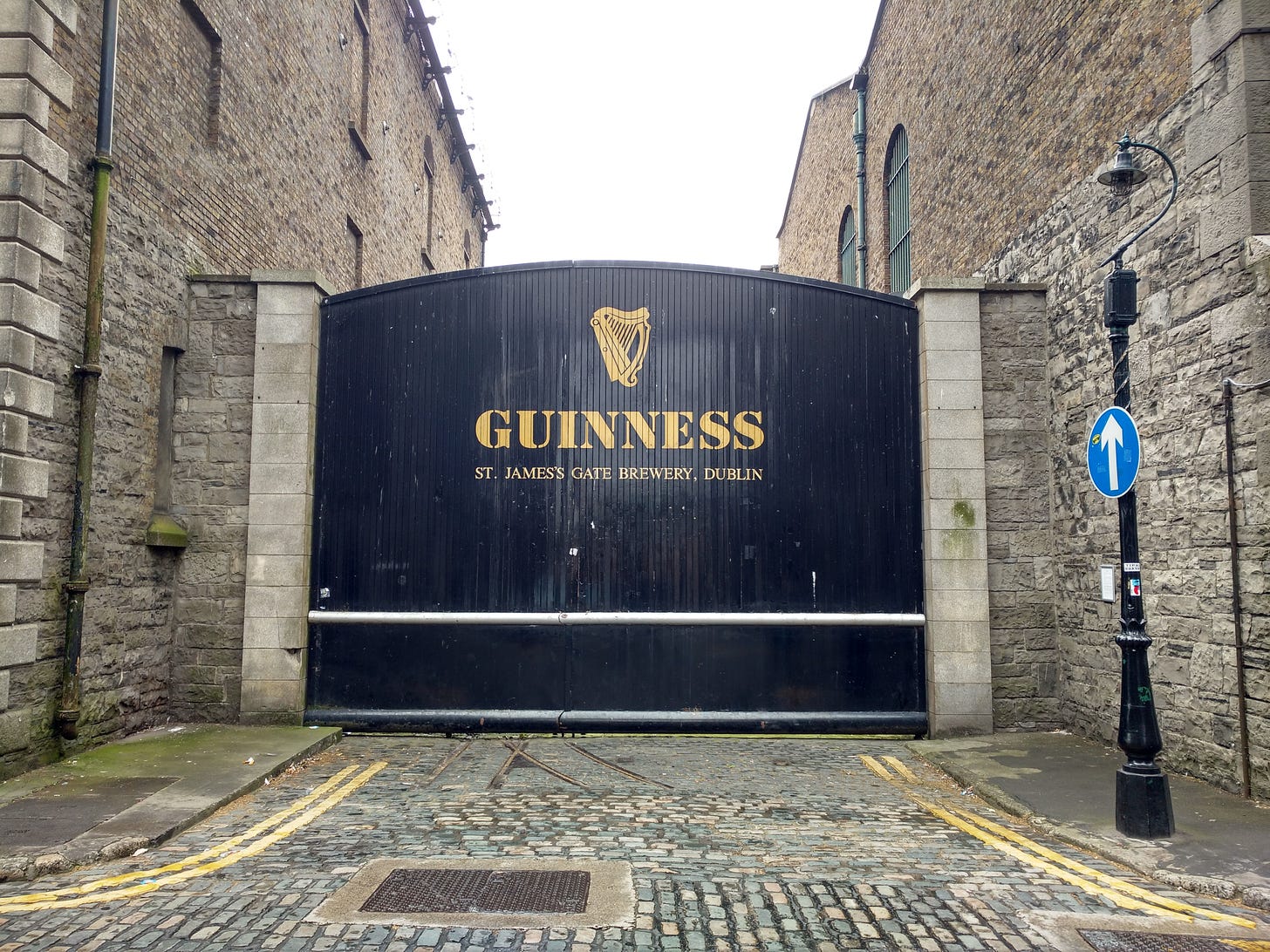 The iconic Guinness Storehouse gates are painted black with gold lettering. Surrounded by cobblestones, they're a tourist landmark.