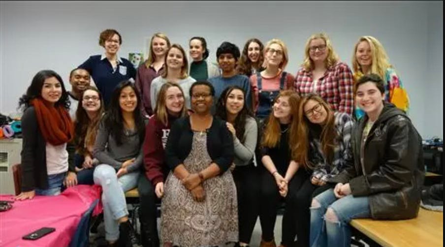 Dr. Gretna Wilkinson educator surrounded by 18 os her students.