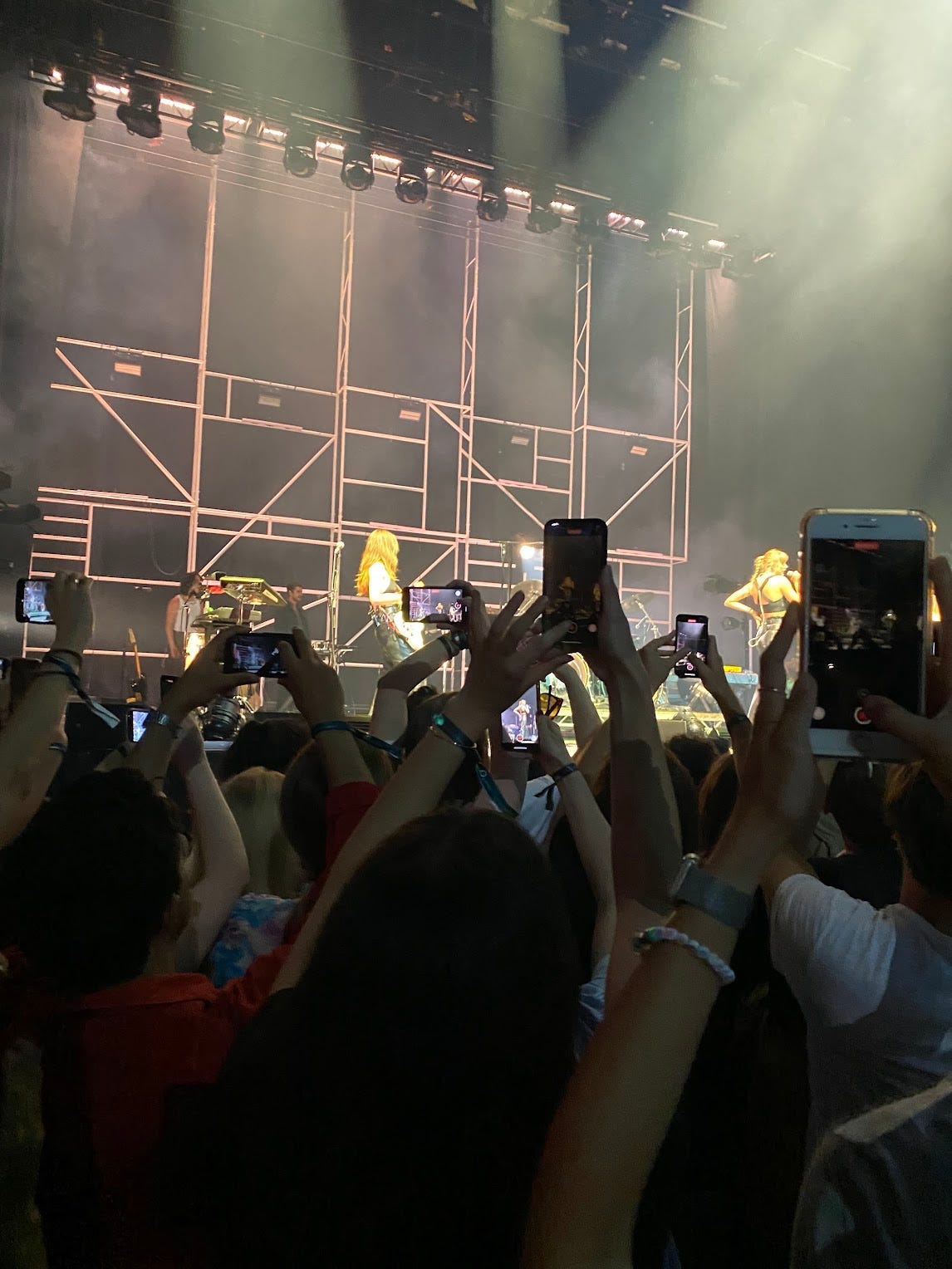 A crowd with hands and phones up in the air, partially blocking the view of the stage at the O2 while HAIM plays with special guest Taylor Swift.