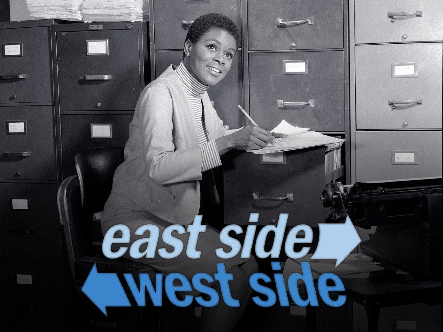 This black-and-white promotional image shows Cicely Tyson as Jane Foster in the 1963-1964 American television drama East Side/West Side. Foster sits on a chair in front of a large bank of filing cabinets, with pencil and paperwork atop an open filing-cabinet drawer. The series title appears in two different shades of light blue below this drawer. This black-and-white promotional image shows Cicely Tyson as Jane Foster in the 1963-1964 American television drama East Side/West Side. Foster sits on a chair in front of a large bank of filing cabinets, with pencil and paperwork atop an open filing-cabinet drawer. The series title appears in two different shades of light blue below this drawer.