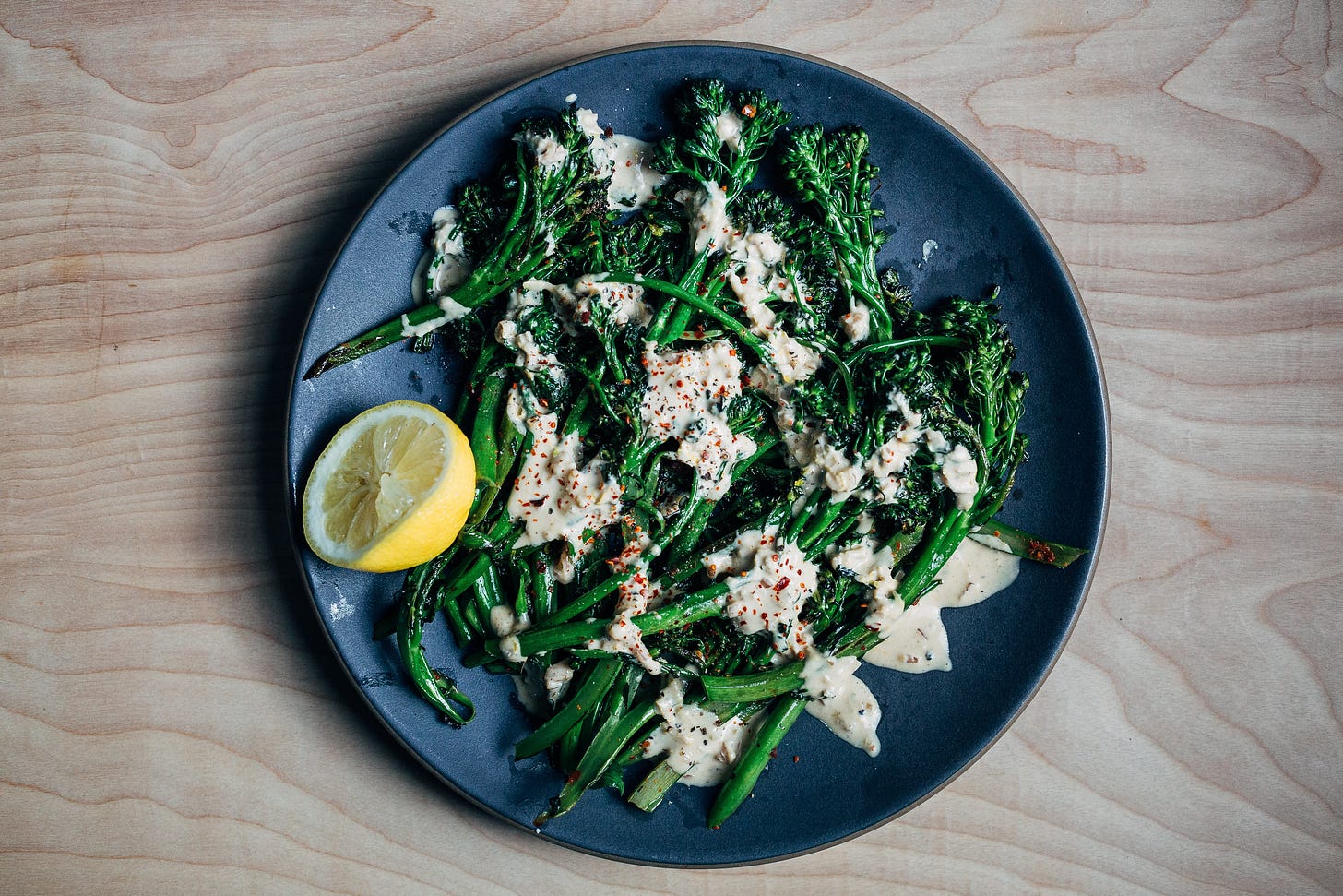 A platter of broccolini drizzled with tahini sauce