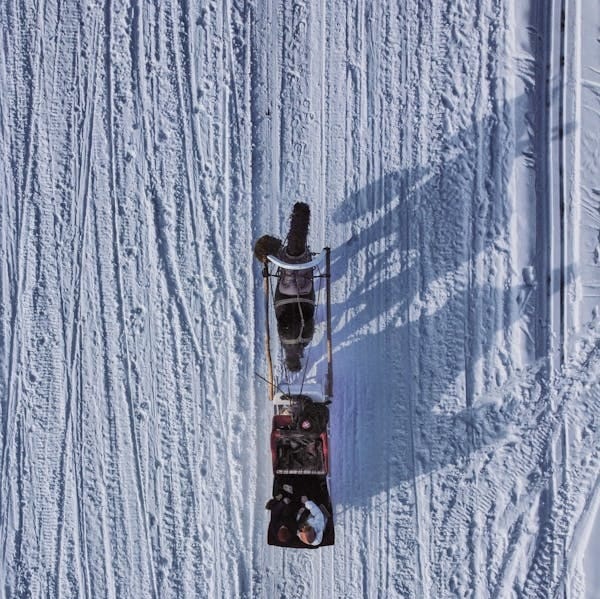 Free Aerial shot of horse pulling a sleigh across snowy terrain on a winter day. Stock Photo