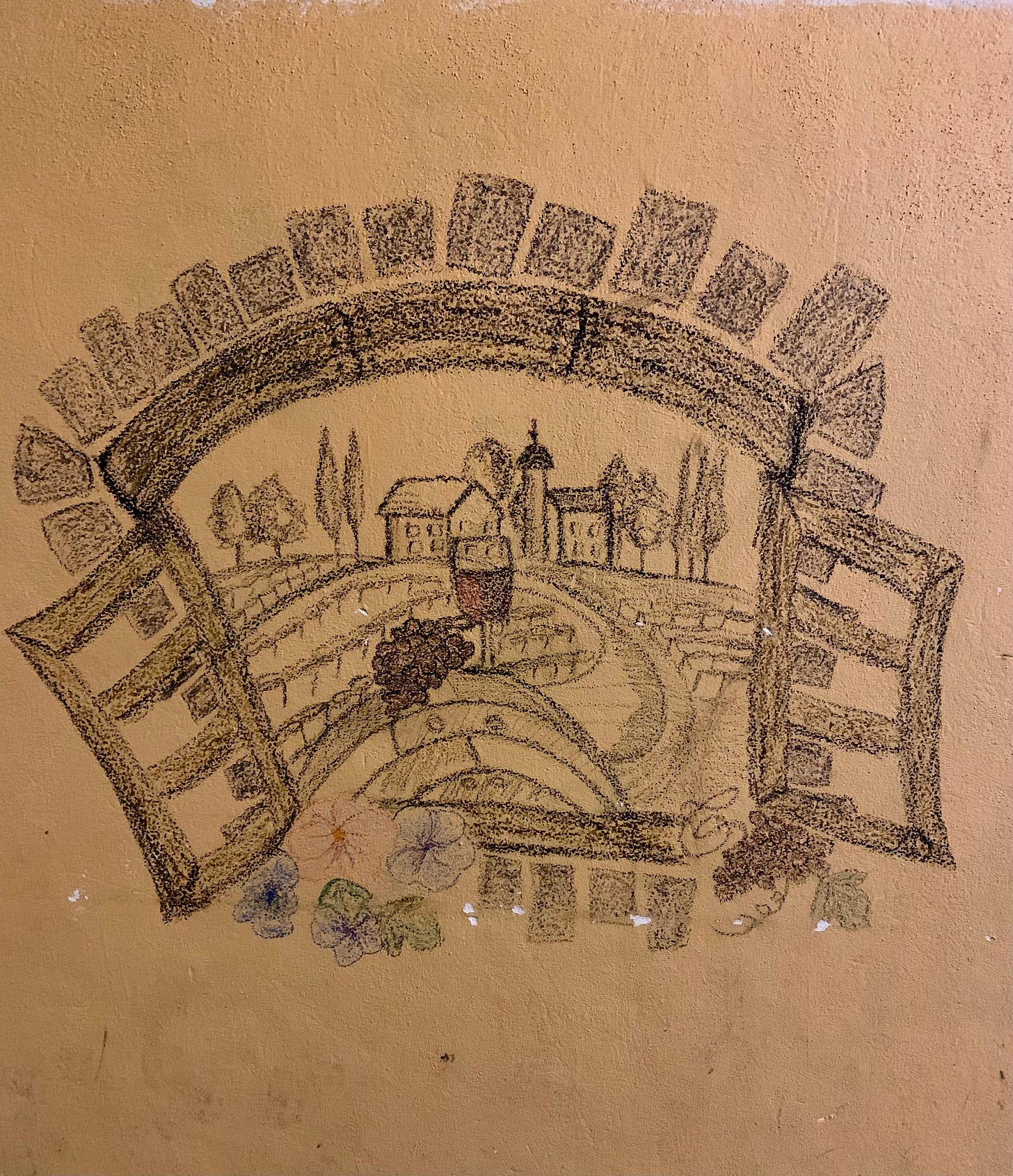 on a wall someone has drawn a picture of an open window and a view of a winery in the distance and a wine barrel with a bunch of grapes and a glass of wine in the foreground