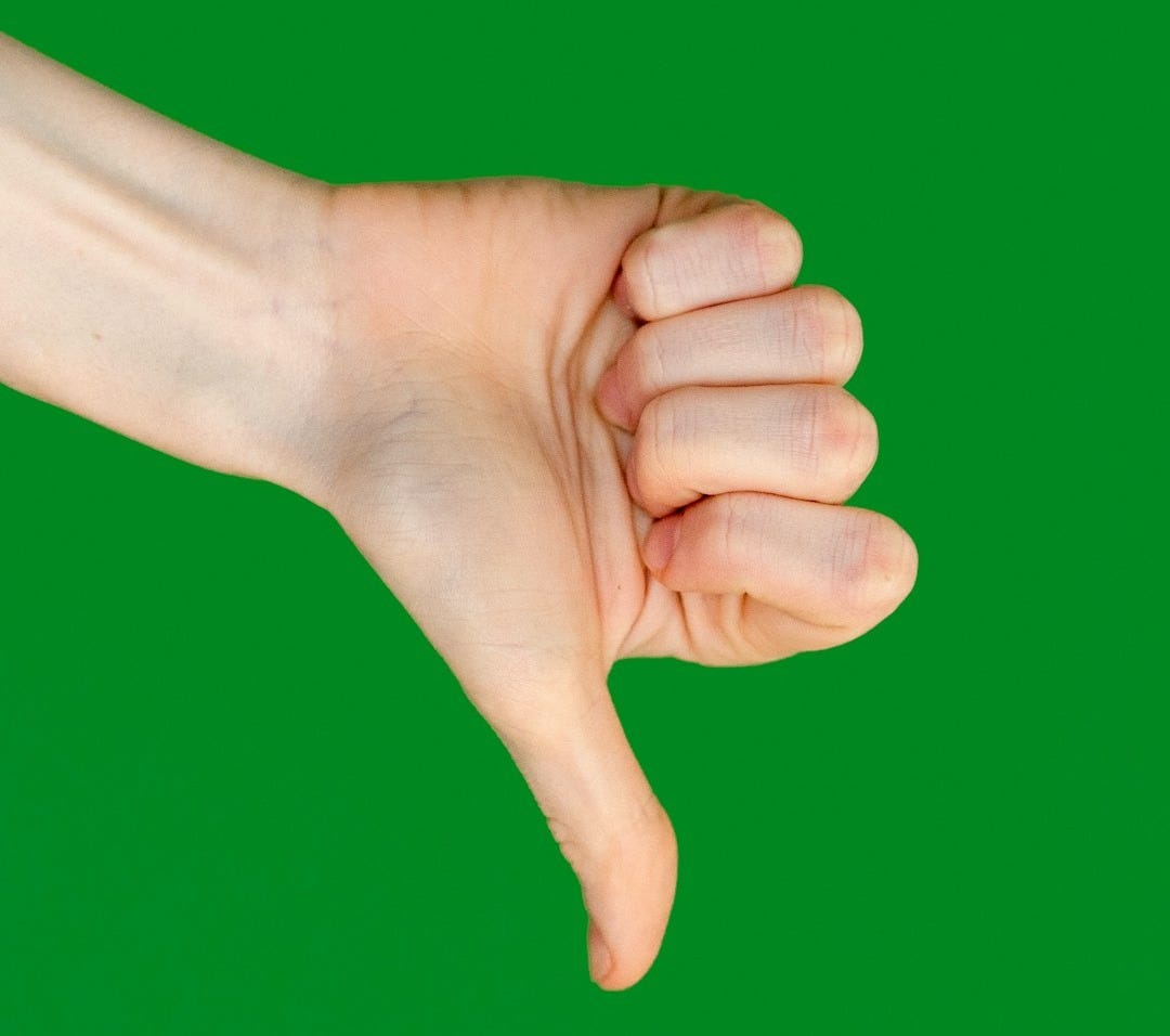 a person's hand holding a cell phone in front of a green background