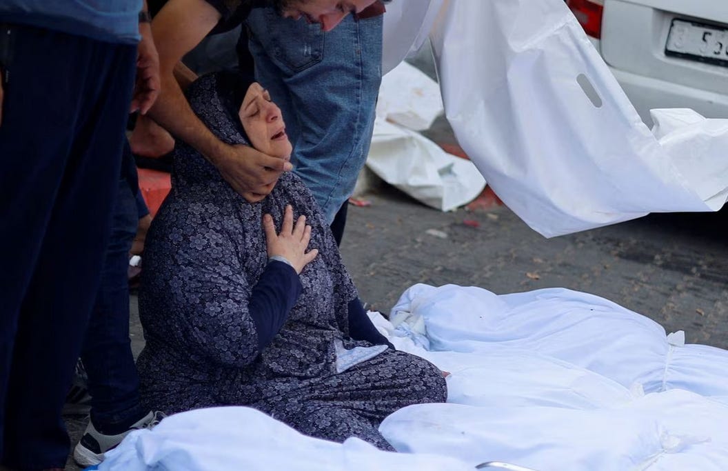 A woman collapsed to her knees mourns relatives killed by an Israeli airstrike at a Gaza City Hospital. 