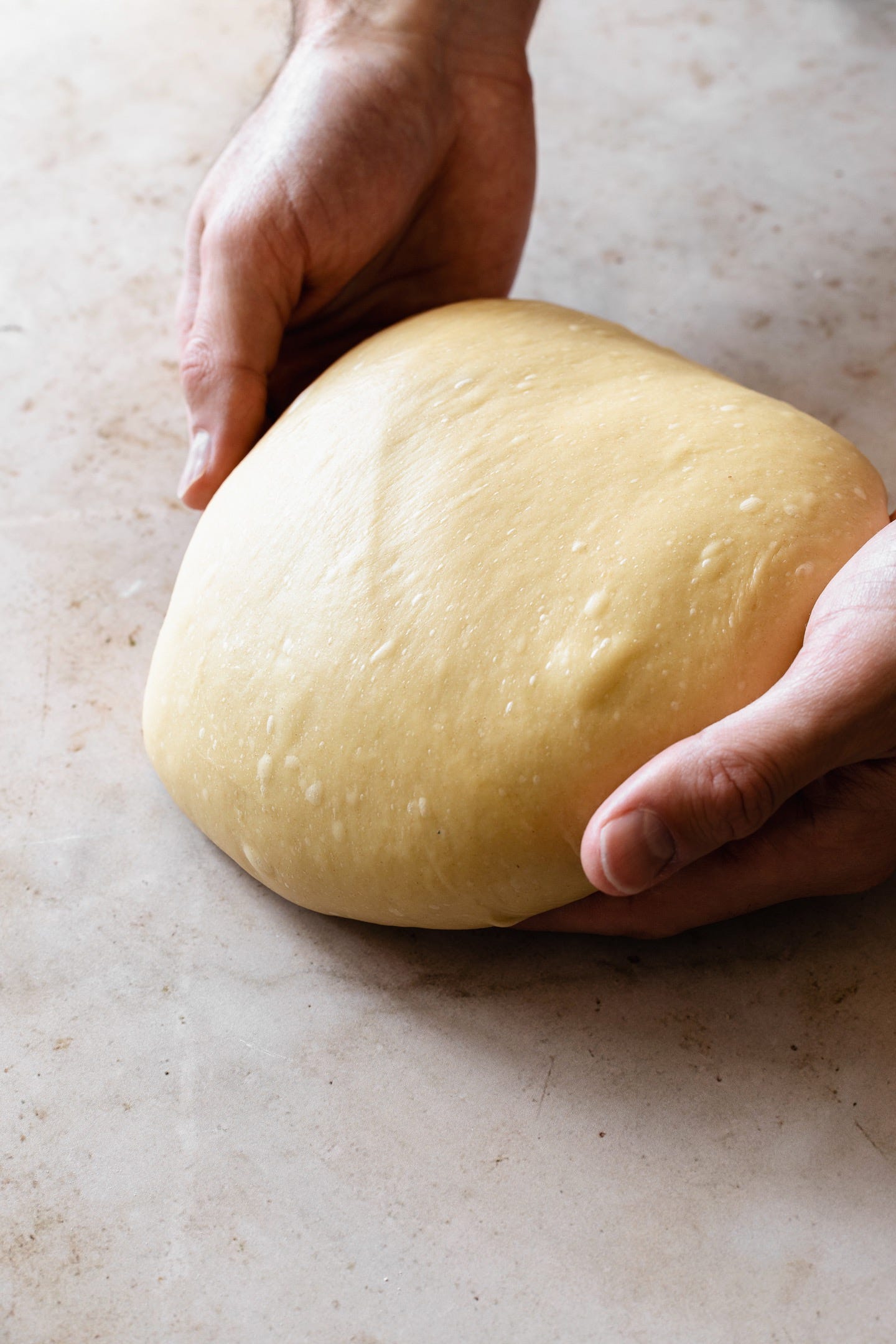 Hands holding vegan olive oil brioche dough