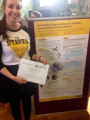 Stephanie Harris holding a certificate for her poster prize, with her poster in the background. A plastic octopus is attached to the poster.