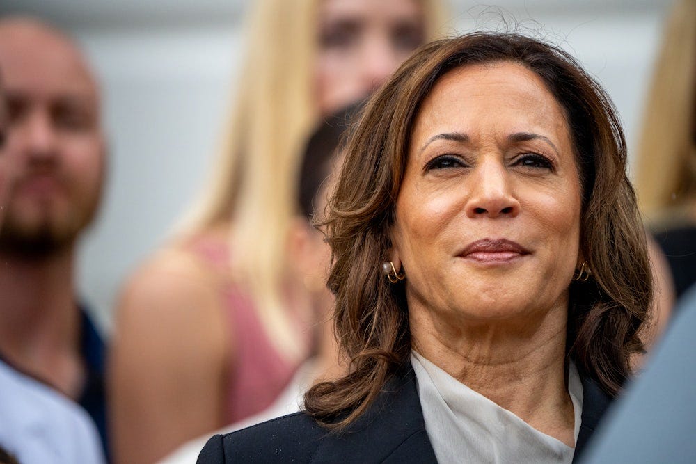 Kamala Harris smiles slightly as she stands in a crowd at the White House 