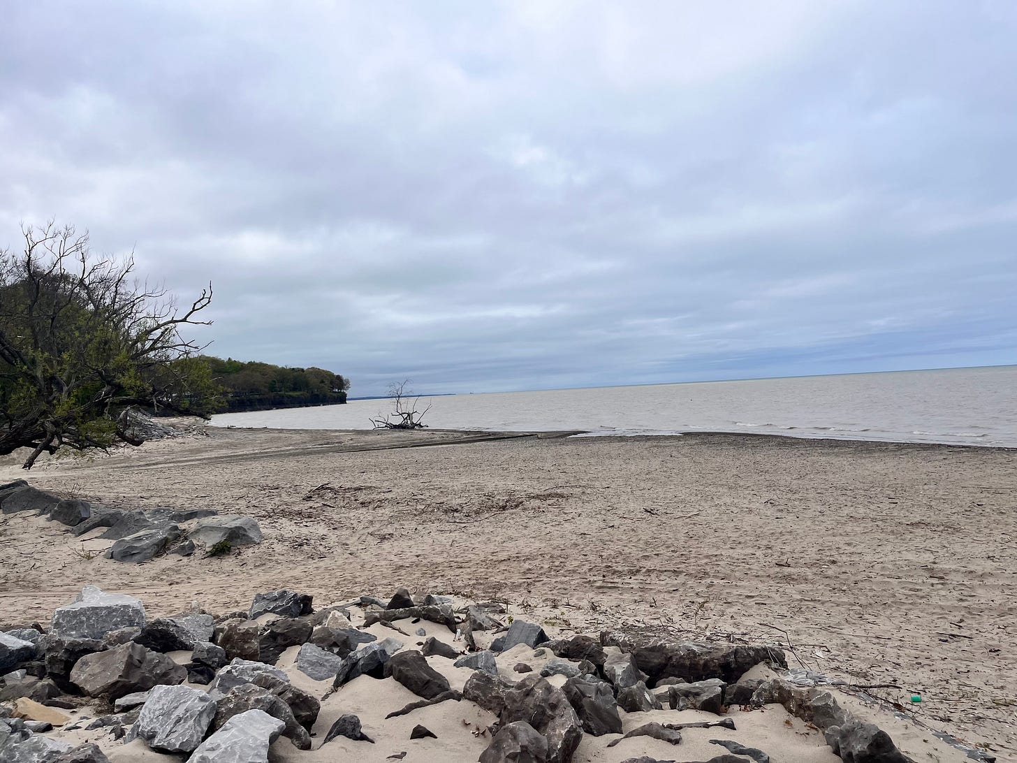 beach sand and rocks in the foreground, with Lake Erie stretching out into the horizon