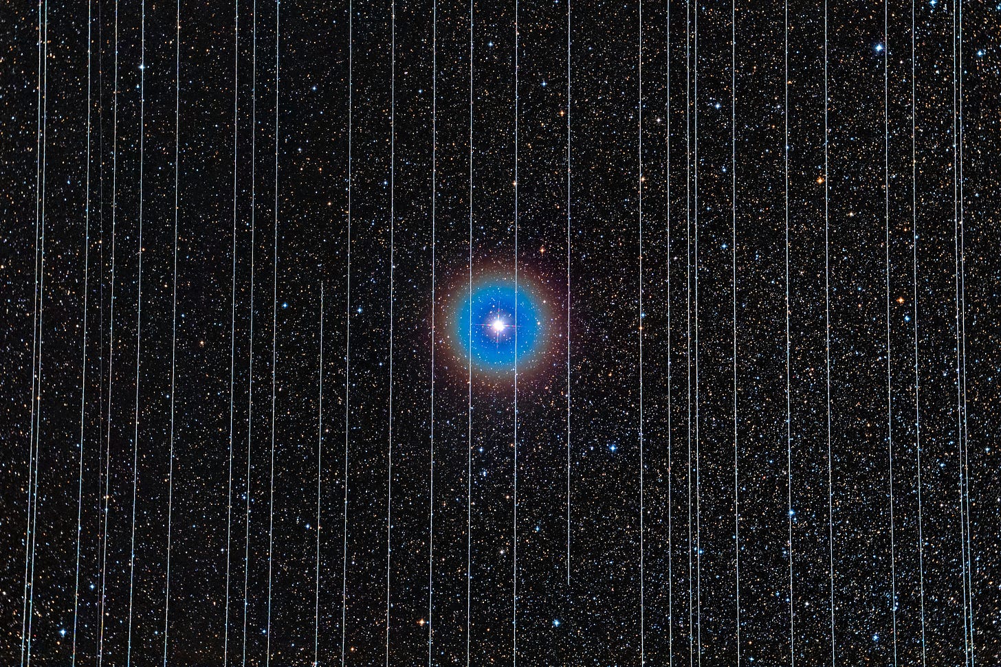 A long exposure photograph of a dark sky centered on the double star Albireo, appearing large and bright while surrounded by smaller, more distant stars. Several white lines run vertically across the whole frame.