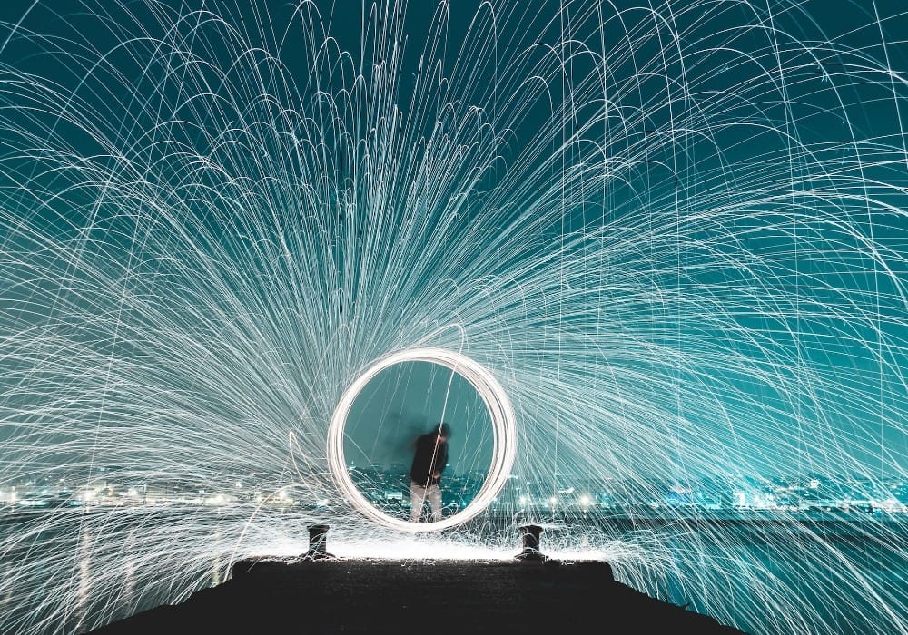 Person spinning fire at twilight on the edge of a city pier illustrating what high vibration looks like