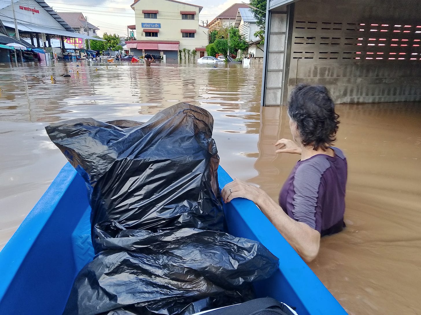 My partner guiding a small plastic boat holding all our belongings through flood waters