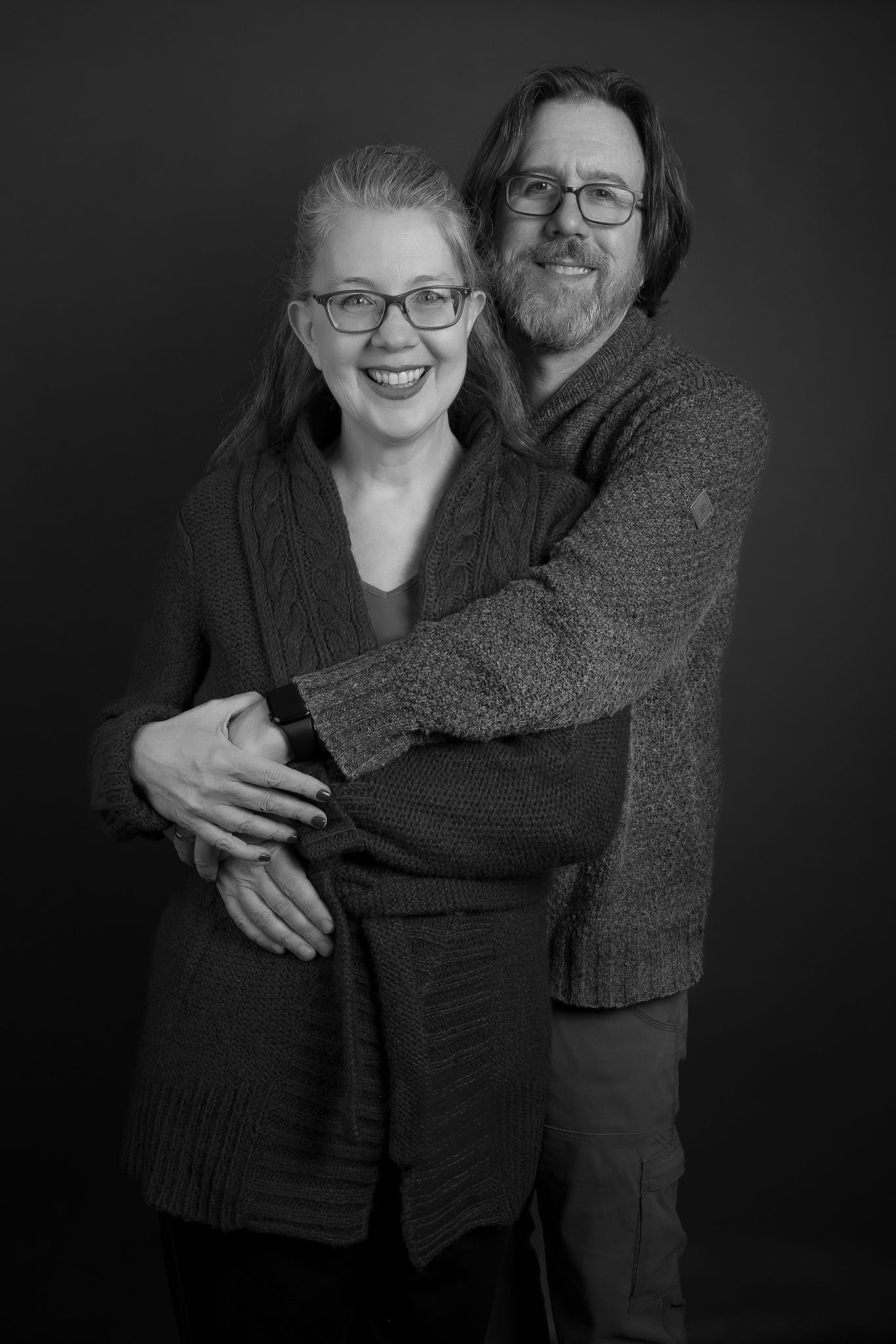 Black and white photo of a man and woman, with the man's arms around her.