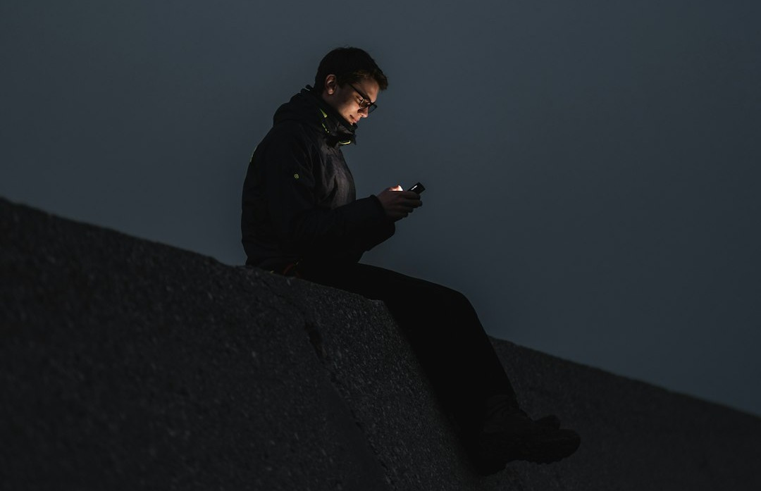 man in black jacket sitting on the edge of a building man in black jacket sitting on the edge of a building