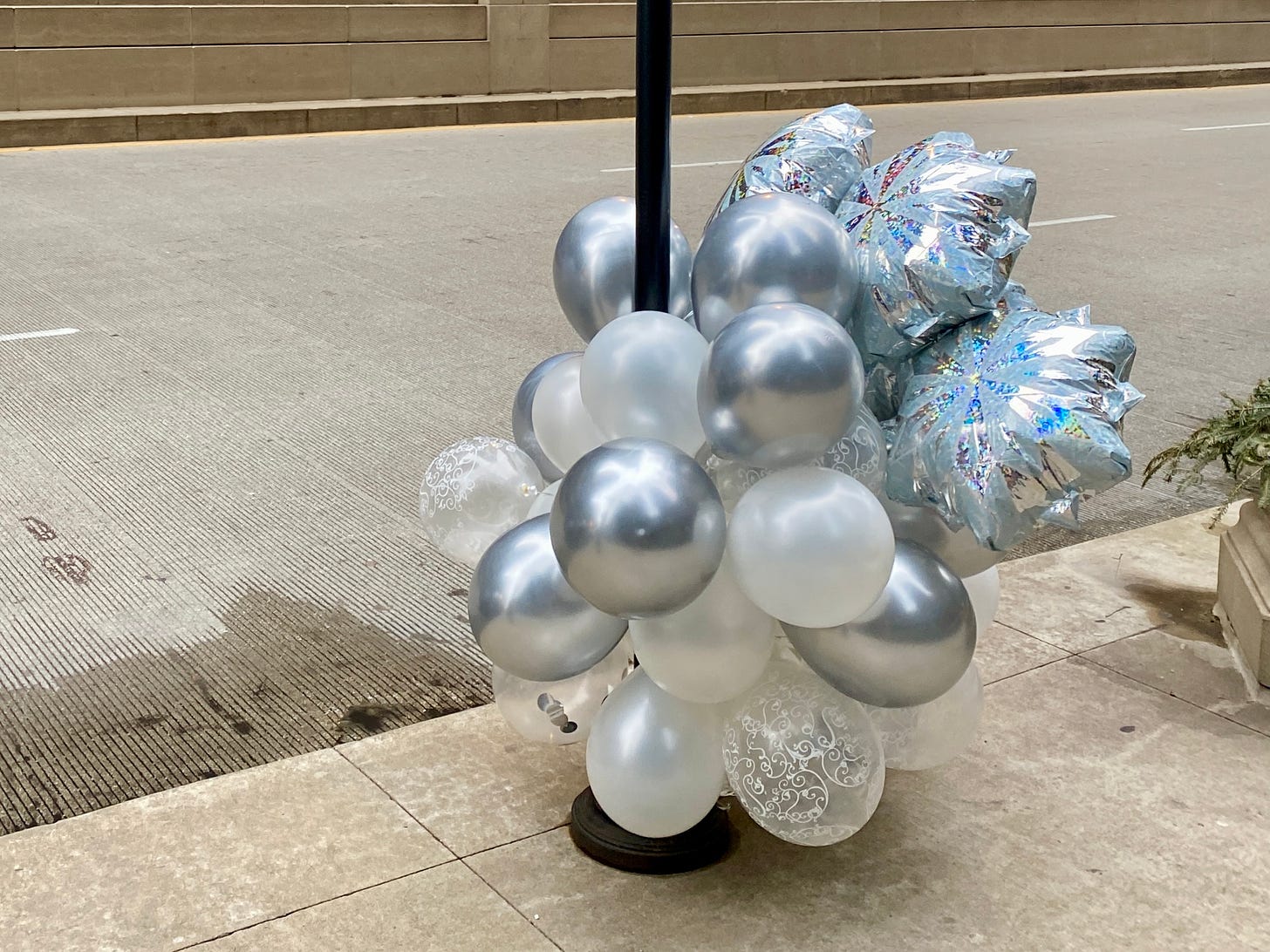 A photograph of white and silver balloons tied to a sign post in Chicago. I took this in 2023.