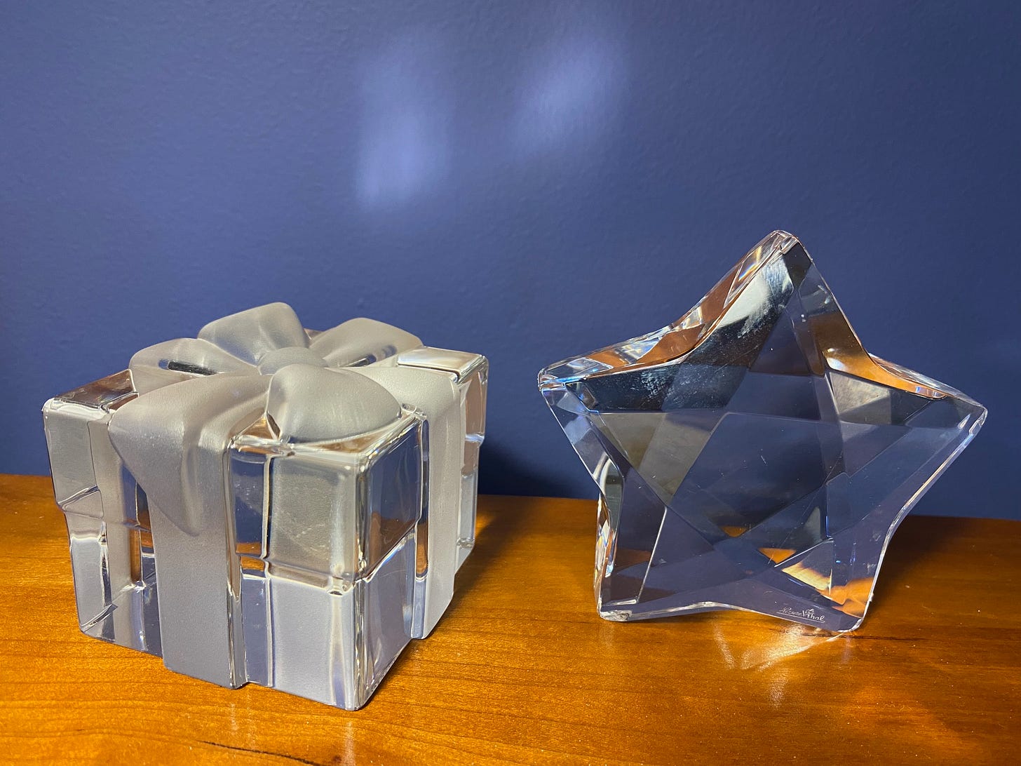 Crystal cube gift box with bow and crystal star on wooden dresser with blue wall in background.