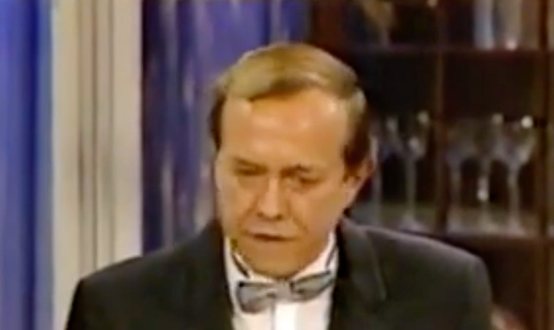 Douglas Marland has brown hair, wearing a gray bow tie and a black jacket.