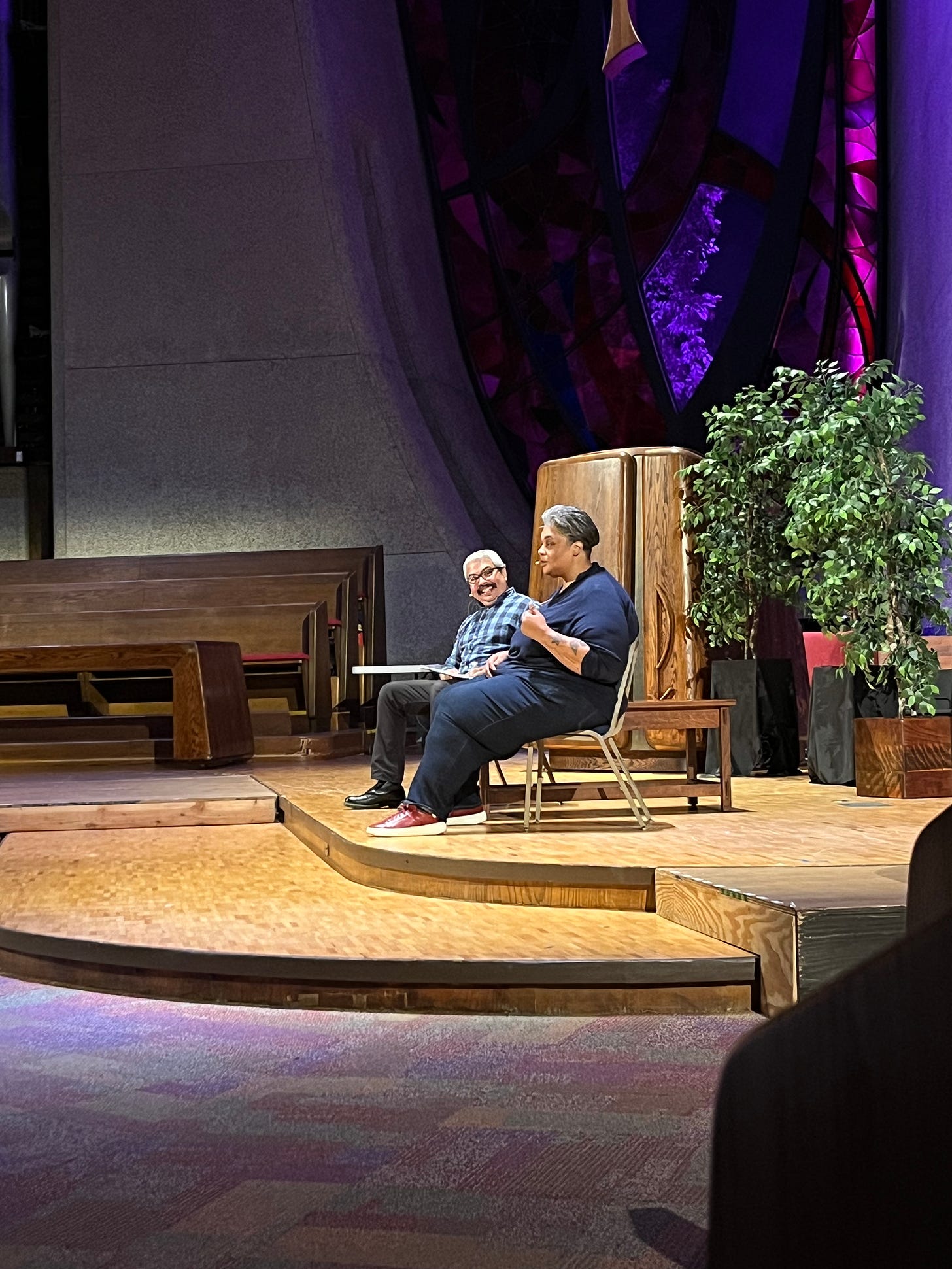 A man and Roxanne Gay seated on a church stage.