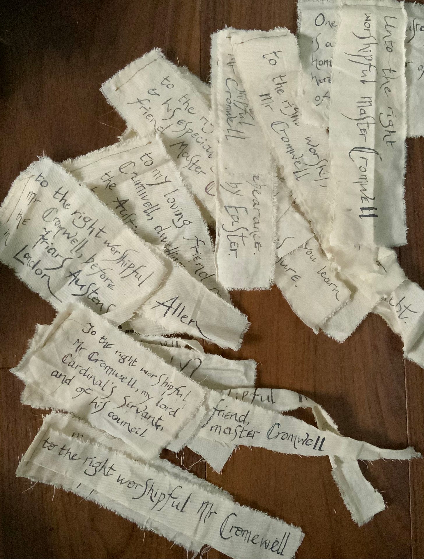 Fabric scraps - unbleached calico - bearing inked letters representing correspondence sent to Thomas Cromwell in 1527.