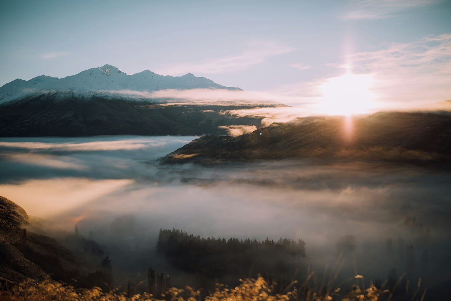 Image of sunrise over gentle mountains with foggy valleys.