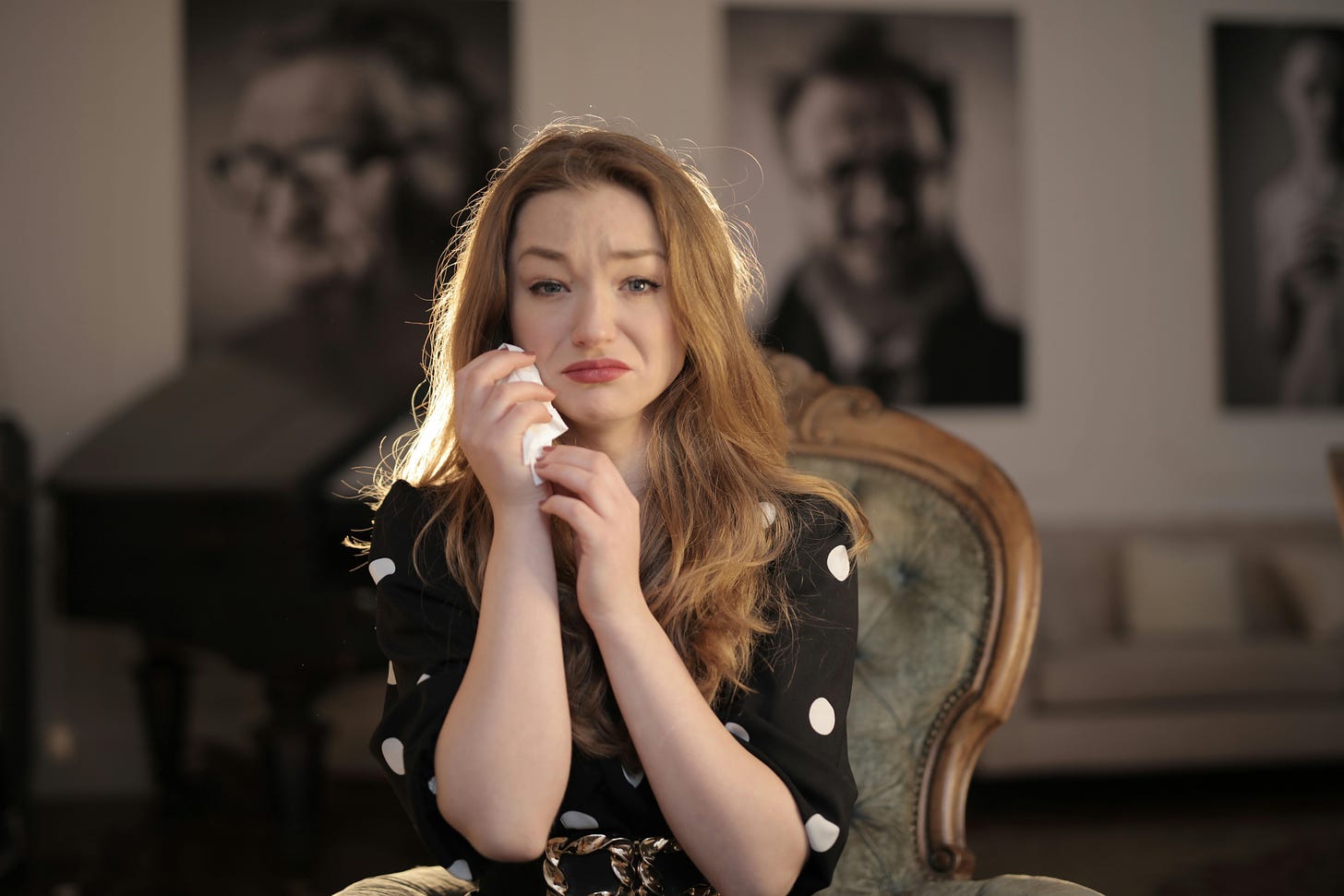 A woman holds a tissue and stares despondently at the camera.