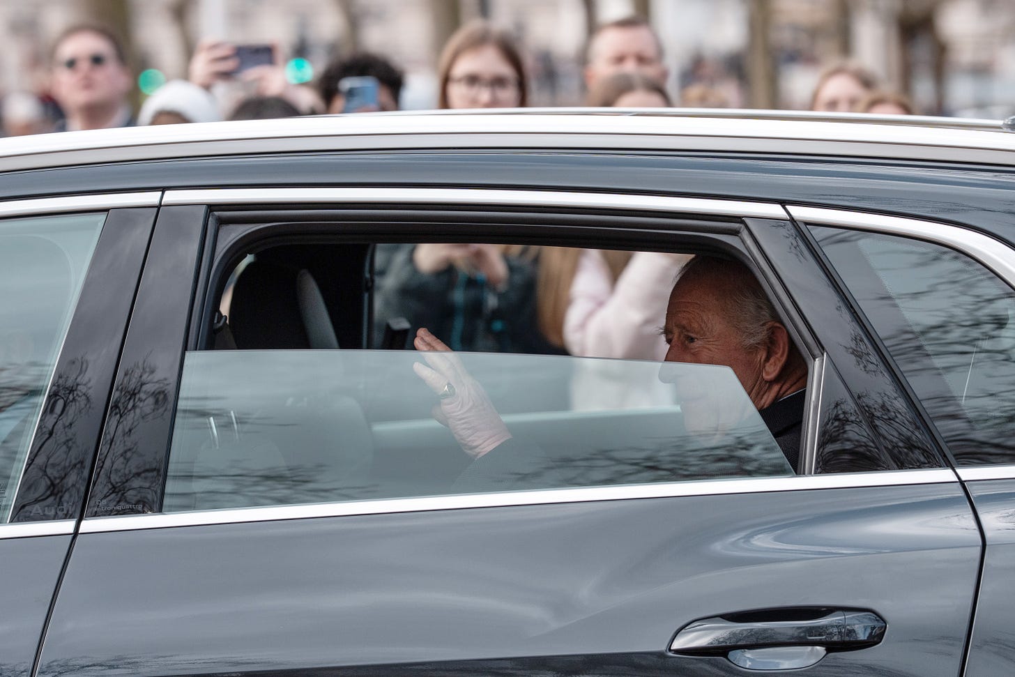 King Charles waves from dark car