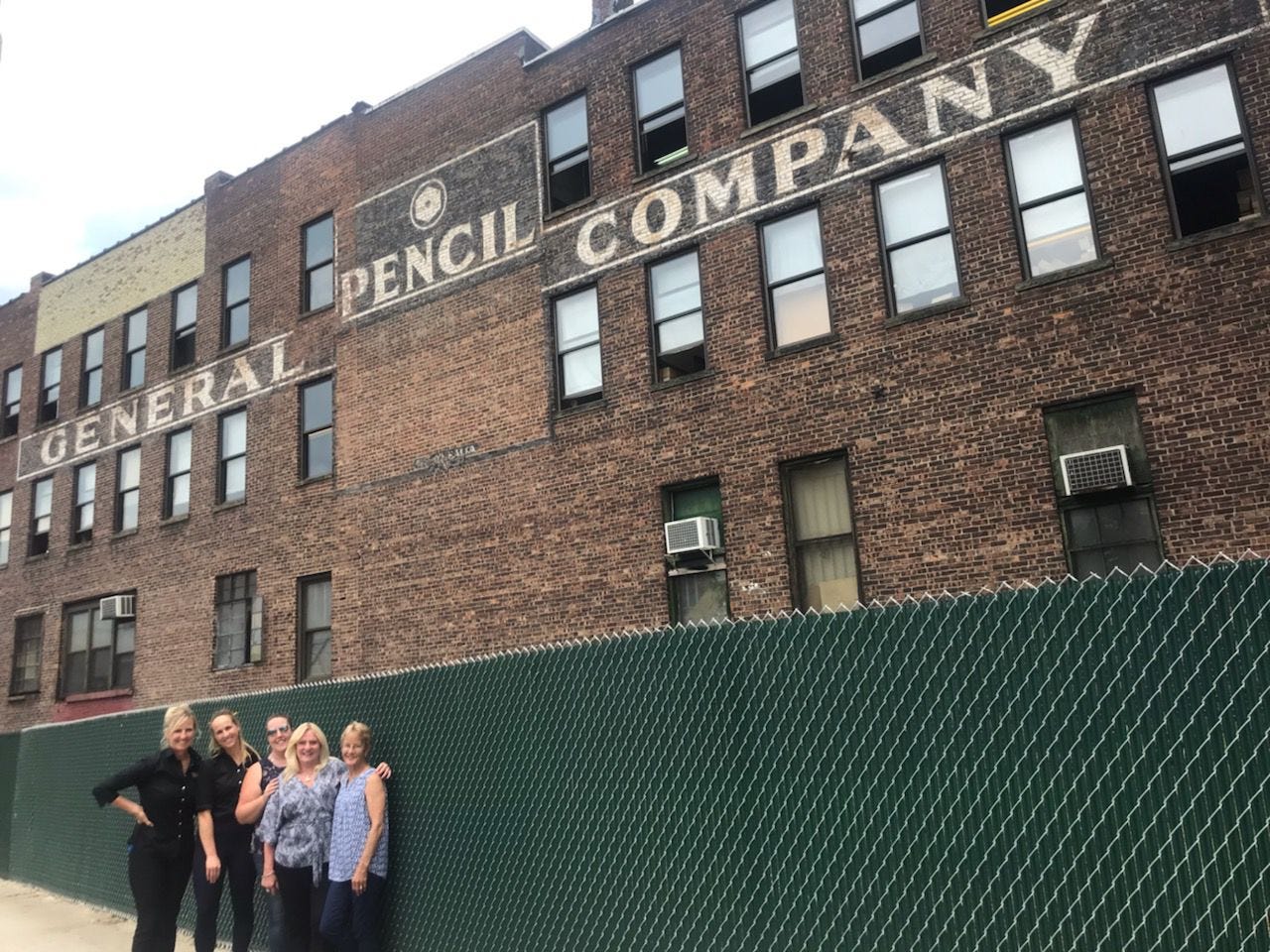 Photo of the outside of the General Pencil Company with five people standing in front of it. Photo of the outside of the General Pencil Company with five people standing in front of it.
