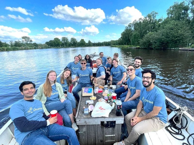 A group of people, presumably the Churned team, sitting in a boat on a lake. They are wearing blue t-shirts with the Churned logo and appear to be enjoying a sunny day outdoors.