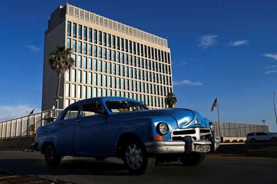 An old American car passes by the U.S. Embassy in Havana.