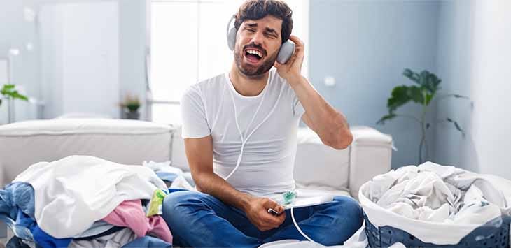 Photo of a man listening to his dirty laundry through headphones.