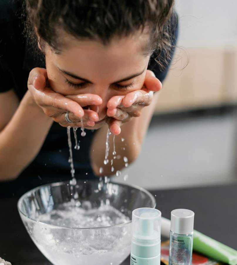 Stock photo of a woman splashing water on her face.