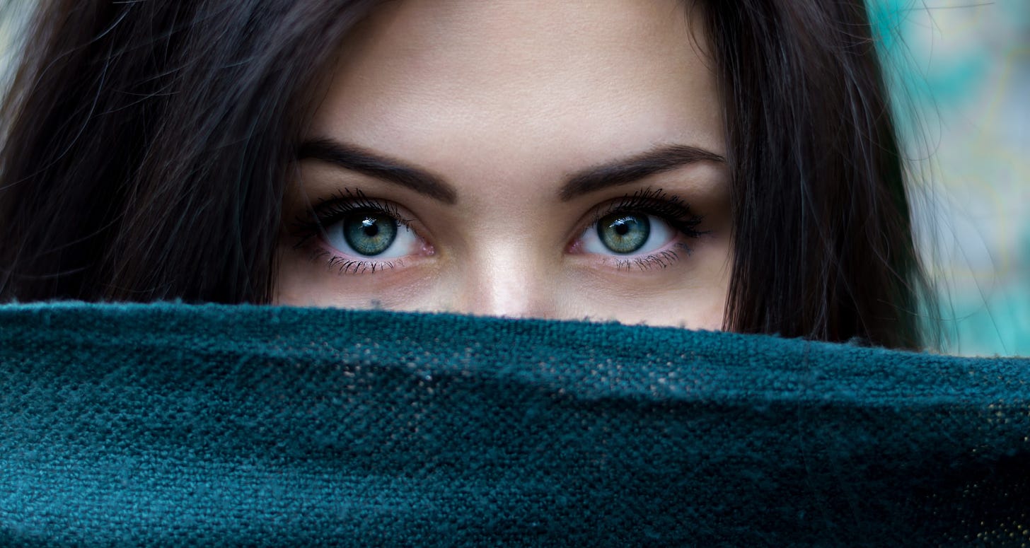 A girl with blue eyes looking from behind a scarf