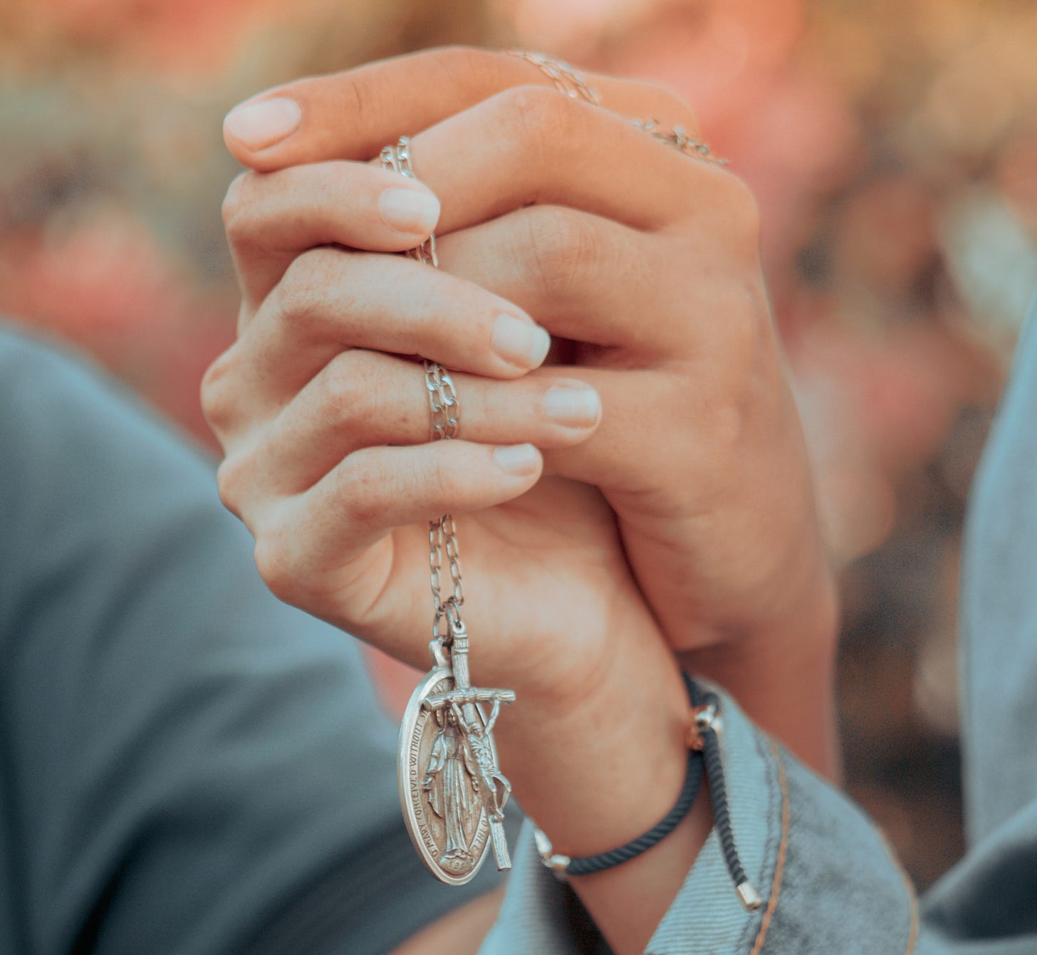 Couple hands with crucifix and miraculous medal