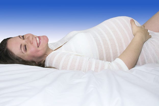 Pregnant Mother laying down smiling in white dress Pregnant Mother laying down smiling in white dress