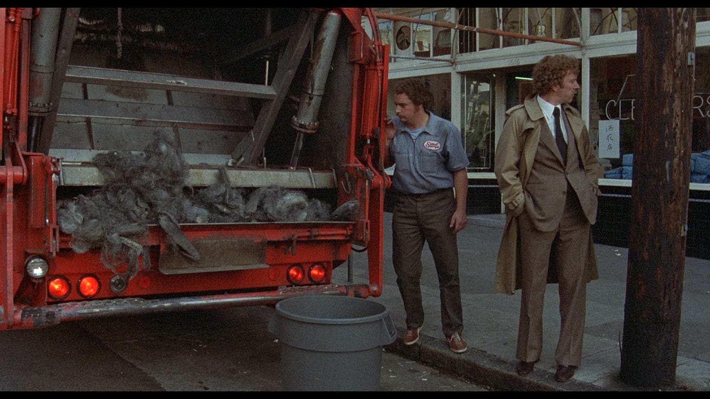 Donald Sutherland stands beside a garbage truck disposing of some mysterious remains.