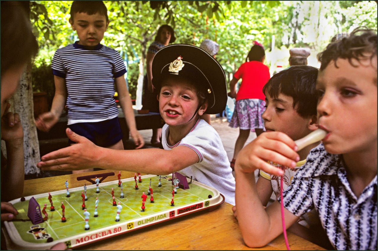 Ian Berry A boy in toy soldier’s hat plays table football whilst another sports a black eye, in the grounds of a local kindergarten. Odessa, Ukraine. 1982. © Ian Berry | Magnum Photos
