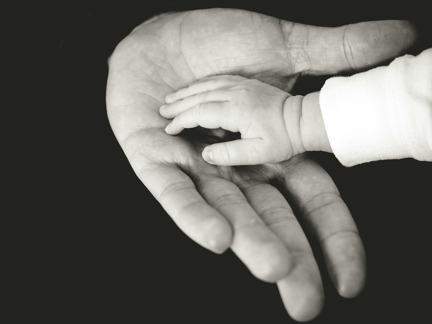 a baby's hand in an adult's hand